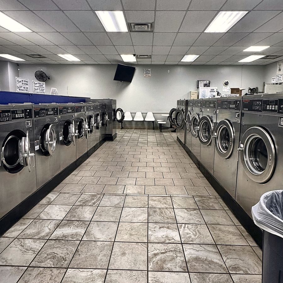 Rows of Speed Queen washing machines in every size along both sides of the aisle at Coin Laundry in La Vergne